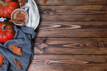 Cup of hot autumn spicy drink on warm soft scarf thanksgiving orange pumpkins, spices on dark brown wooden table. Top view with rustic background and copy space