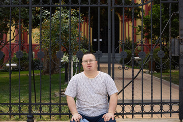 Man with down syndrome.
A man with Down syndrome sits in front of a building with a beautiful...