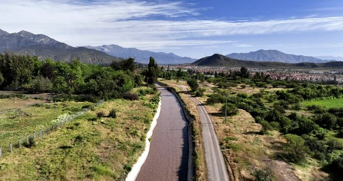 Aerial of water canal next to road overlooking scenic idyllic relaxing mountainous countryside in rural area of Chile