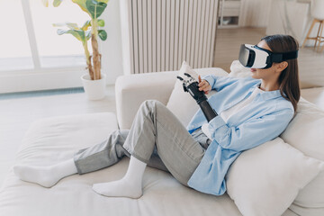 Relaxed young woman with a prosthetic arm enjoys a virtual reality experience, comfortably lounging...