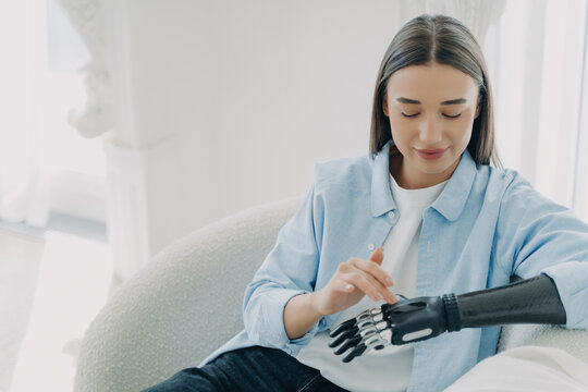 Content woman with bionic hand gently touching her forearm, showcasing the blend of humanity and technology