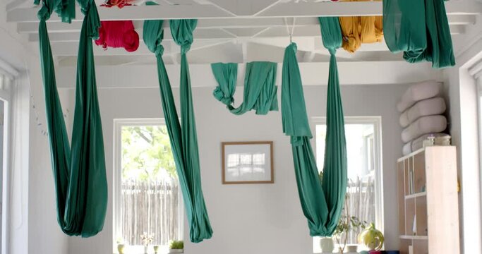 Empty white room with hanging gymnastic sashes over plants and wardrobe, slow motion