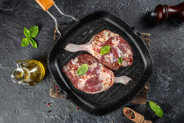 raw duck legs in pan on a dark background. top view. copy space for text