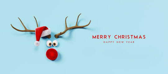 Reindeer with red nose and Santa hat on light blue background. Christmas greeting card design with...