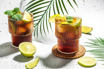 Cuba Libre with Lime and Ice mint in the glass on a light background top view. copy space