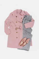 Classic pale pink trench coat with jeans and loafers. Fashion spring or autumn outfit. Women's stylish and elegant clothes with accessory.  Flat lay, top view, overhead.