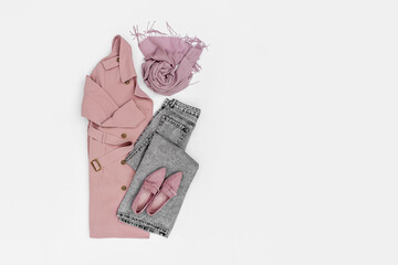 Classic pale pink trench coat with jeans and loafers. Fashion spring or autumn outfit. Women's stylish and elegant clothes with accessory.  Flat lay, top view, overhead.