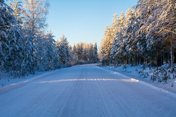 Obraz premium Snowy winter road with trees. Winter conditions in the North. Copy Space