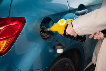Attractive young woman refueling car at gas station. Female filling diesel at gasoline fuel in car...
