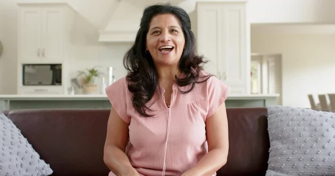 Happy biracial senior woman having video call and smiling in sunny living room, slow motion
