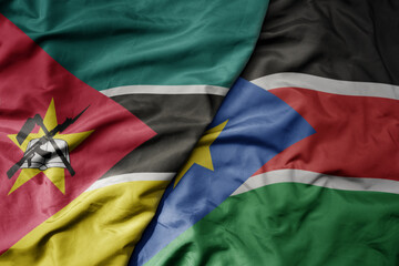 big waving national colorful flag of south sudan and national flag of mozambique .