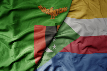 big waving national colorful flag of comoros and national flag of zambia .
