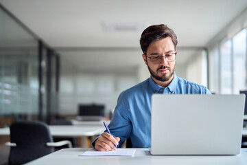 Young busy latin business man employee worker looking at laptop computer watching online webinar or...