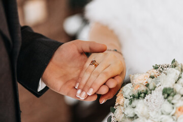 The groom puts a ring on the bride's finger. Exchange of rings. Happy couple celebrating wedding...