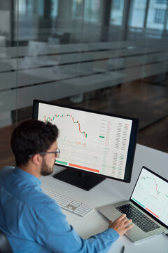 Busy business man trader broker analyst investor using laptop computer analyzing stock trade crypto market digital data investing finances in stockmarket working in dark office. Top view vertical.