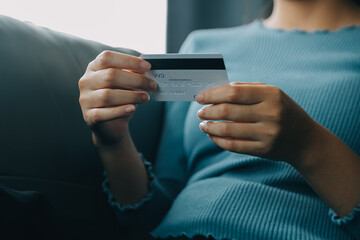 A credit card in the hands of a young businesswoman pays for a business on a mobile phone and on a desk with a laptop.