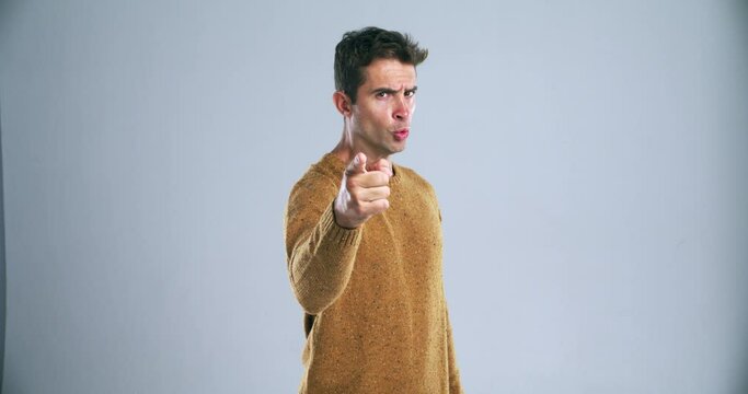Threat, challenge and hand gesture of a man in studio on a gray background for fighting or conflict. Portrait, pointing or come here and an angry young person warning you with violence or frustration