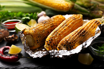 Grilled corn on the cob in tin foil on kitchen table healthy gluten free food background