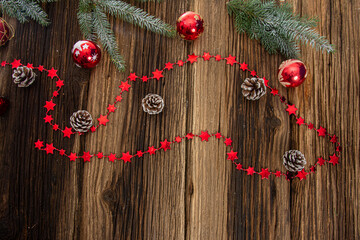 Christmas composition. Fir branches  red Christmas ornaments on a wooden brown background. Space for text  top view. Background