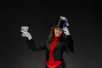 A portrait of a magician in a magician's costume and black top hat performing magic tricks with...