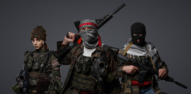 Trio of radical extremists from the Middle East in camo attire, keffiyeh, and balaclava, striking a pose on a gray backdropbackground