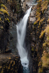 Fototapeta na wymiar Silverfallet waterfall flowing between dark rocks, Kiruna region, Swedish Lapland