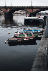 Fototapeta premium Photo of boats on the Vltava river in Prague Czechia at the evening. Colorful vessels on the river in city - dark urban photo.
