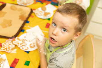 A boy at a master class prepares and paints New Year's gingerbread