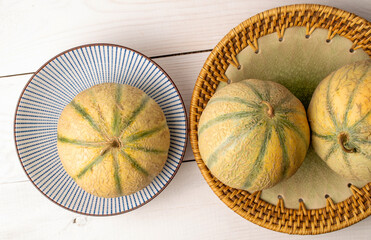 Three fragrant juicy, organic melons, with ceramic plates, close-up, on a white wooden table, top view.