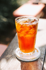 A large glass of cool iced tea on a wooden table. Stylish design of cool drinks for summer