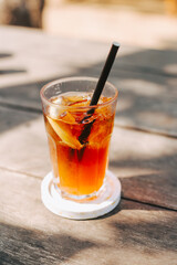 A glass of cool tea with ice and a paper straw on a wooden table