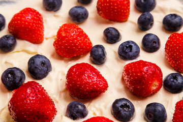 Fresh juicy strawberries and blueberries blueberries in thick whipped cream close-up