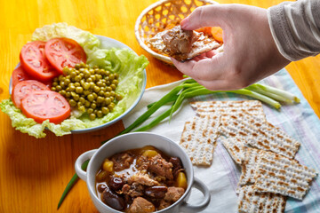 A woman's hand takes a piece of stewed lamb flatbread at the Iftar meal