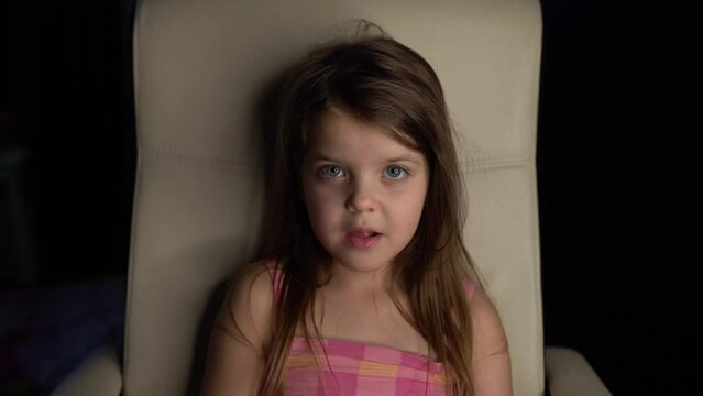 smiling little girl looks at camera and eating lollipop