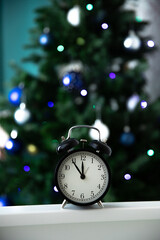 The New Year's clock against the background of the Christmas tree shows 23.55, five minutes before the New Year