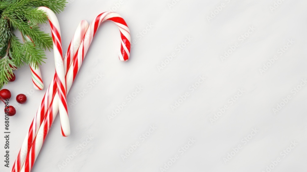Poster a couple of candy canes sitting on top of a table next to a branch of a christmas tree with two cand