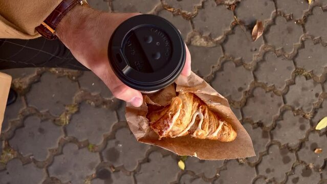 POV, male hand carry a takeaway coffee with croissant at the autumn day