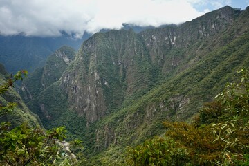 Obraz premium Mountains covered with greenery under a cloudy sky at Machu Picchu, Peru.