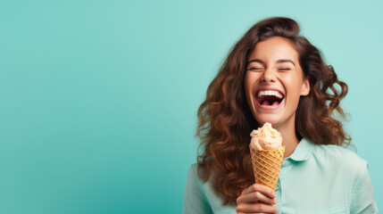 A woman wearing a big smile as she enjoys a waffle cone filled with colorful ice cream on a mint blue background, closeup. Copy space. - obrazy, fototapety, plakaty