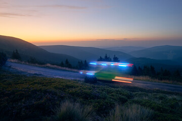 Light trails of ambulance car of emergency medical service on mountain road at night. Themes...
