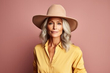 Portrait of a blissful woman in her 50s wearing a rugged cowboy hat against a pastel brown background. AI Generation