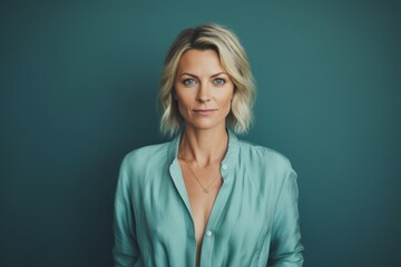 Portrait of a merry woman in her 40s wearing a chic cardigan against a soft teal background. AI Generation