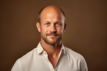 Obraz premium Portrait of a satisfied man in his 40s wearing a simple cotton shirt against a soft brown background. AI Generation