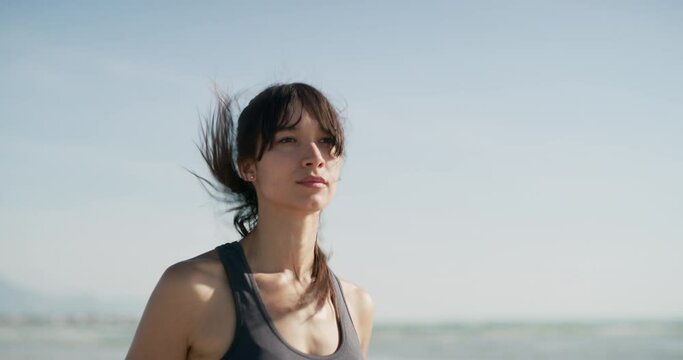 Woman, running and fitness on beach for workout, training and cardio wellness, marathon or outdoor journey. Young person, athlete or runner by ocean or sea for exercise, resilience and challenge