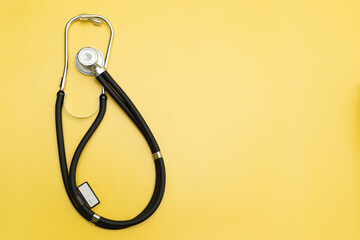 Stethoscope on yellow background and space for text, medical equipment for banner