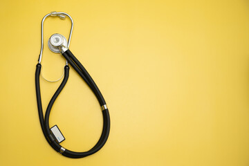 Stethoscope on yellow background and space for text, medical equipment for banner