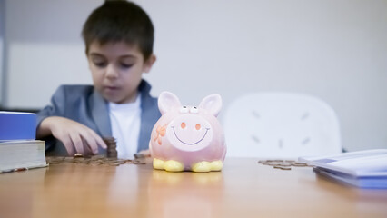 Cute child boy collecting money from piggy bank for school books. Savings for education, budgeting....