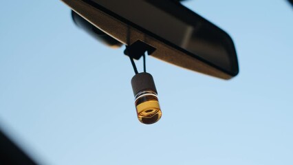 Car air freshener in a bottle hanging on the interior mirror