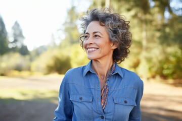 Portrait of a tender woman in her 50s sporting a versatile denim shirt against a bright and...