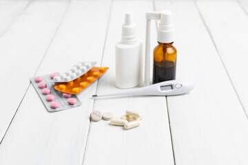 Cold remedies, medicines, thermometer, capsules and pills in a blister pack on wooden table....
